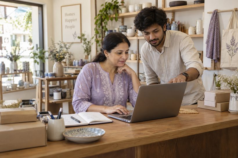 A small-business owner and a helper working together on a laptop